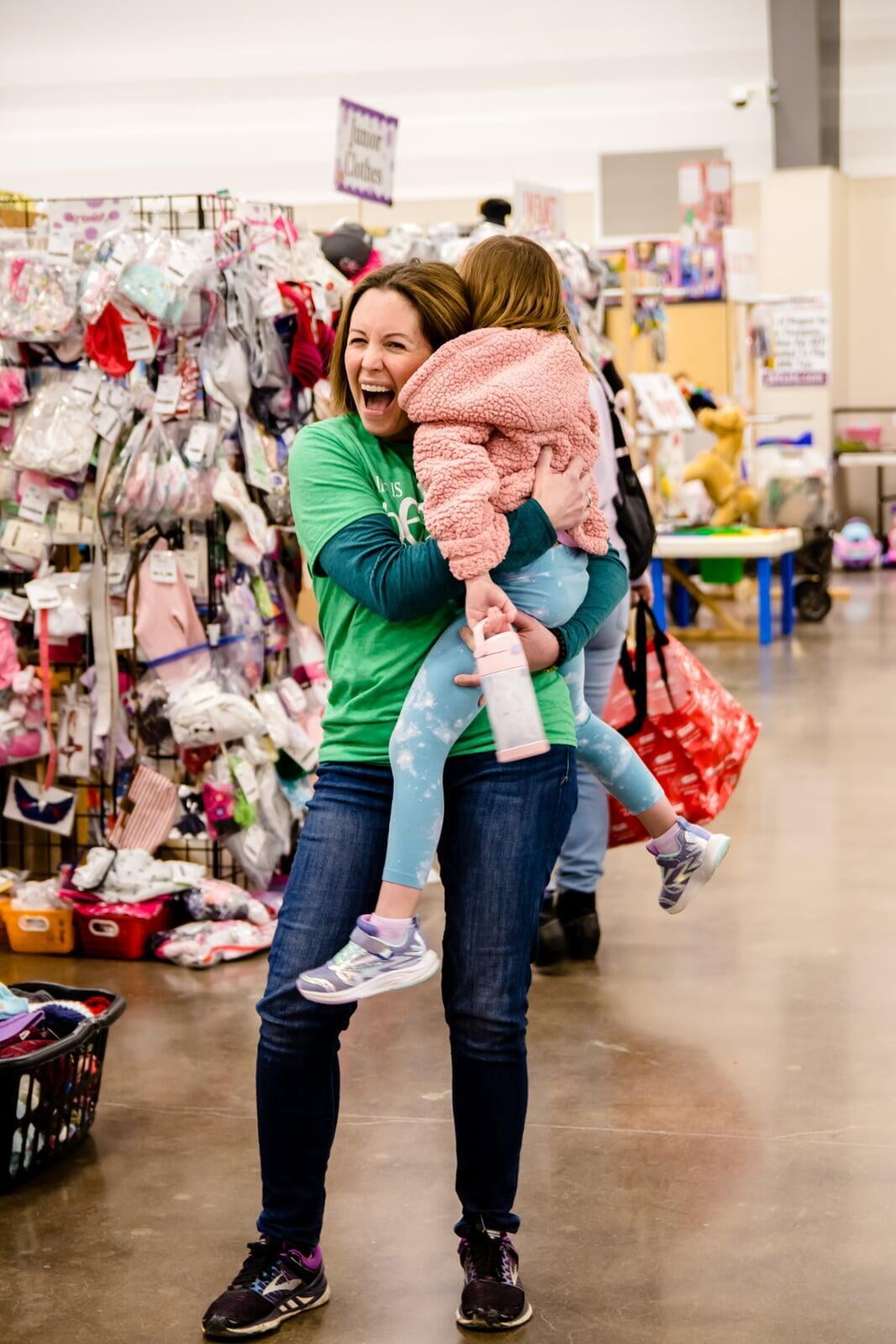 A team member happily hugs a friend's child that was shopping the sale.